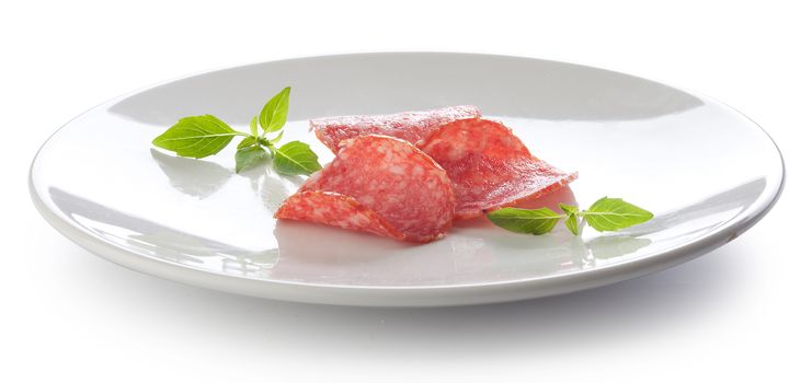 Three pieces of smoked sausage with fresh green basil on the white plate