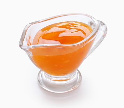 Orange sauce in the transparent sauce-boat on the white