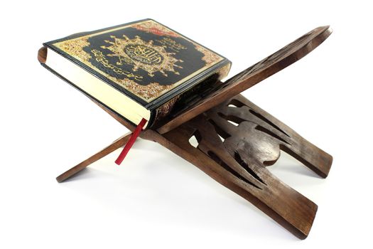 Quran with Quran wooden stand in front of white background