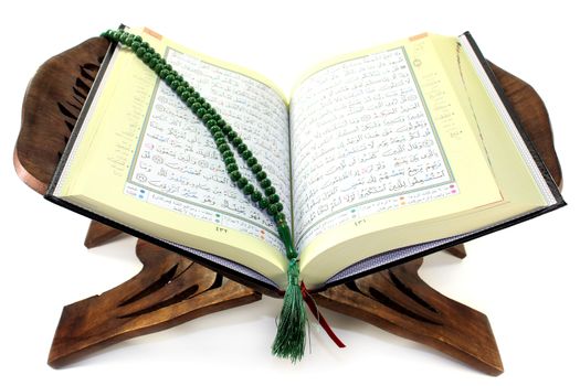Quran with Quran wooden stand in front of white background