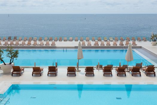 Turquoise swimming pool with modern wooden sunbeds