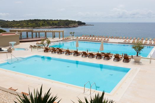 Turquoise swimming pool with modern wooden sunbeds