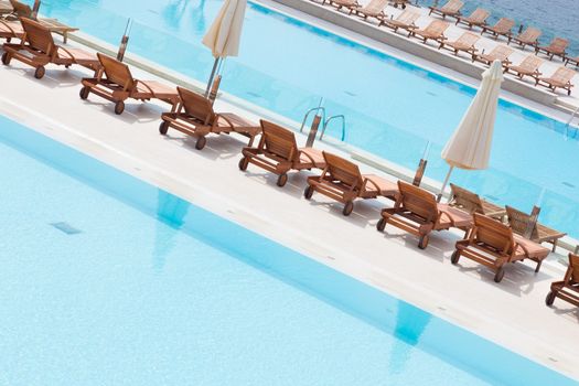Turquoise swimming pool with modern wooden sunbeds