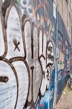 City graffity in Amsterdam. Holland. A small narrow street and typical bicycles. All walls are ornamented