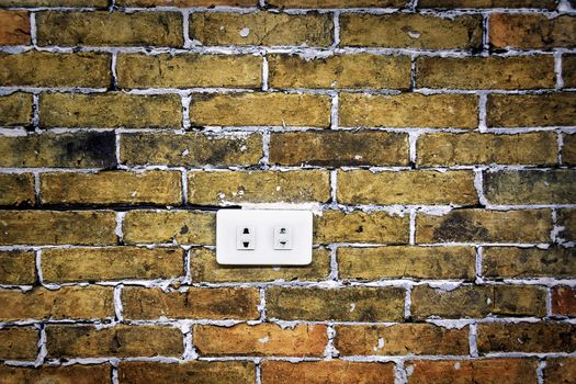 White electrical socket in grunge brick wall