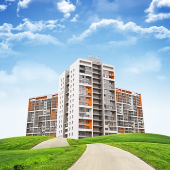 Tall buildings, green hills and road against sky with clouds. Architectural concept