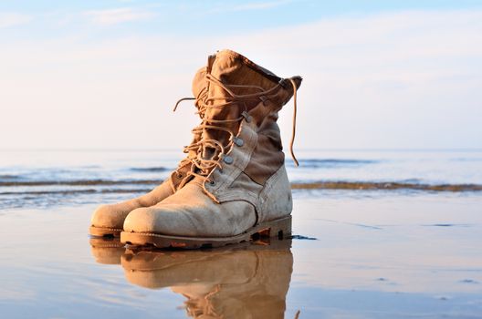 Yellow boots with a shoelaces on a wet sandy beach