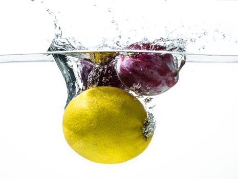 Fresh plums and lemon in water splash