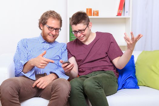 Two guys reading other people's text messages on the sofa 