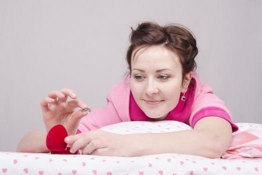 The girl gave a gift in the morning in bed, gave her a ring in the case.