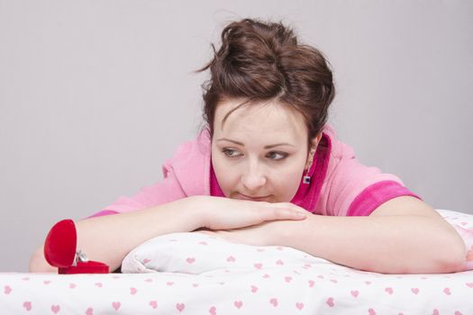 The girl gave a gift in the morning in bed, gave her a ring in the case.