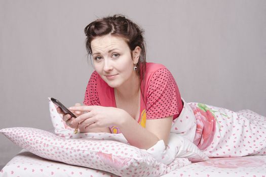 The girl lying in bed and talking on the phone
