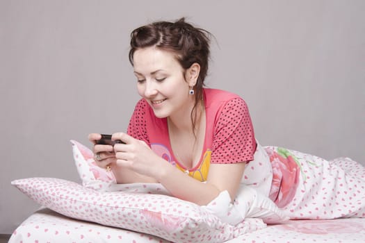 The girl lying in bed and talking on the phone