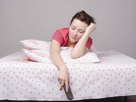 A young girl is Watching TV in bed