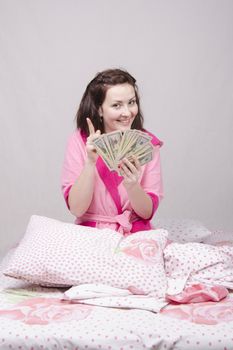 Girl sitting on the bed with a wad of bills for $ 50