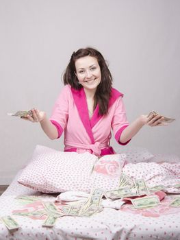 Girl sitting on the bed with a wad of bills for $ 50