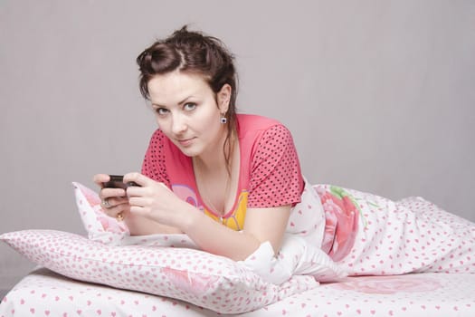 The girl lying in bed and talking on the phone