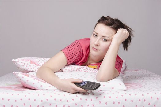 The girl lying in bed and watching TV