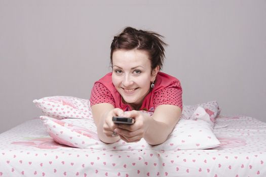 A young girl is Watching TV in bed