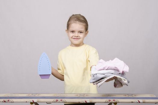 A five year old girl playing in a housewife, and stroking things iron