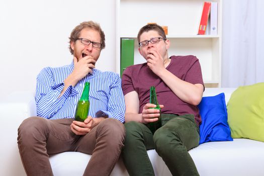 Two guys sittinf on the sofa during party 