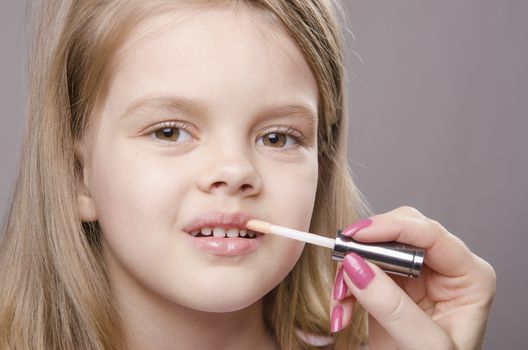 Makeup artist in the process of makeup causes Shine on the lips five year old girl