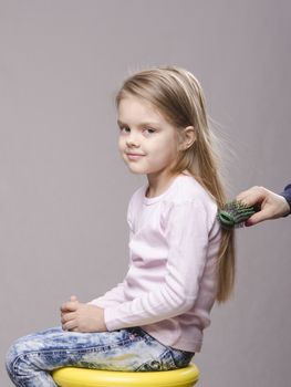 Hairdresser brushing her long hair five year old girl