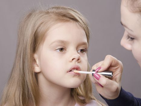 Makeup artist in the process of makeup causes Shine on the lips five year old girl
