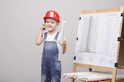 Girl playing Builder talking on the phone behind the blackboard with a drawing of a house