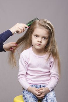 Hairdresser brushing her long hair five year old girl