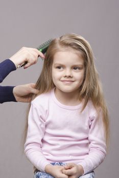 Hairdresser brushing her long hair five year old girl
