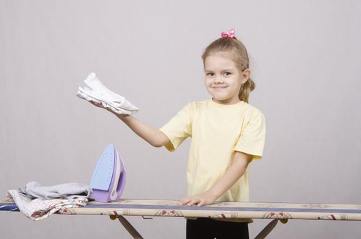 A five year old girl playing in a housewife, and stroking things iron