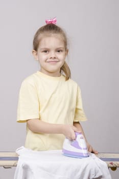 A five year old girl playing in a housewife, and stroking things iron