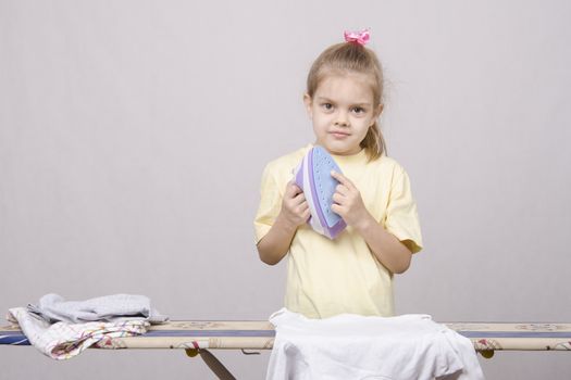 A five year old girl playing in a housewife, and stroking things iron