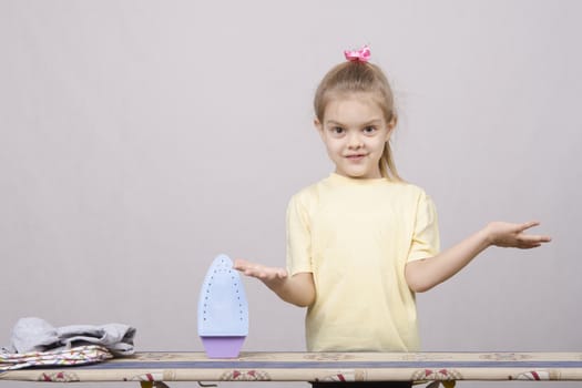 A five year old girl playing in a housewife, and stroking things iron