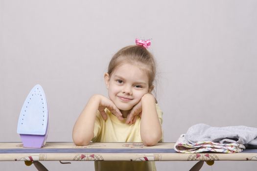 A five year old girl playing in a housewife, and stroking things iron