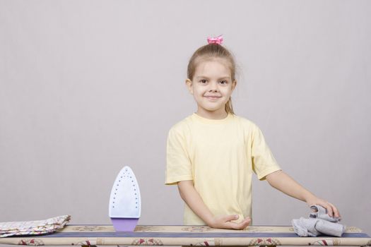 A five year old girl playing in a housewife, and stroking things iron