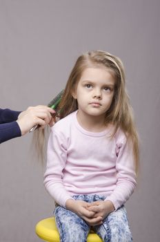 Hairdresser brushing her long hair five year old girl