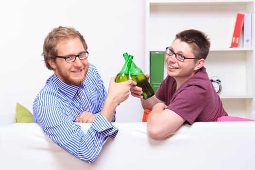 Two young guys with beer on the sofa at home 