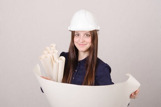 Young woman architect in hardhat standing with blueprints in hand