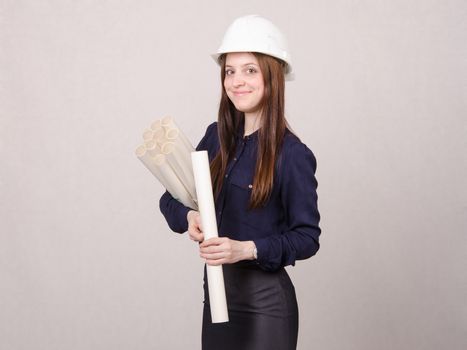 Young woman architect in hardhat standing with blueprints in hand