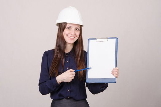 Young woman builder in helmet standing with a folder in hand