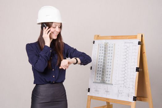 Young woman architect standing at drawing board mounted on the project of a multistory building