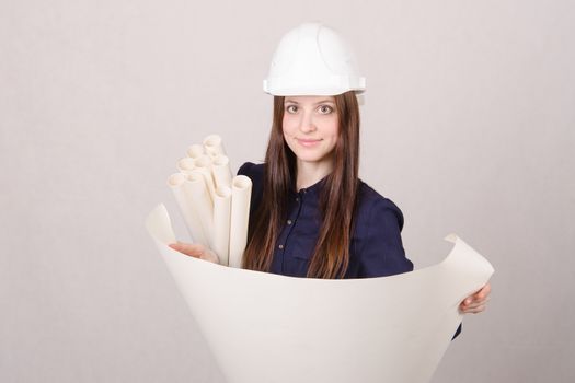 Young woman architect in hardhat standing with blueprints in hand