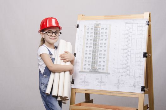 Girl Builder, architect, holding a bunch of drawings, standing at the blackboard with the drawing of the building