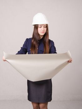 Young woman architect in hardhat standing with blueprints in hand
