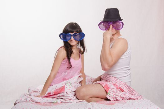 Young couple sitting in bed and each wore big glasses