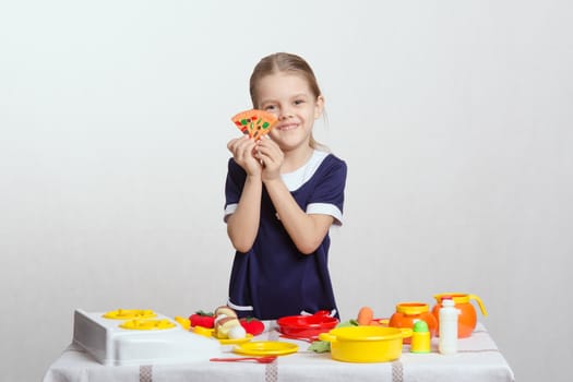 Five year old girl plays children's dishes at a table covered with a cloth