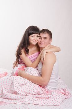 Young couple sitting in bed and hugging each other