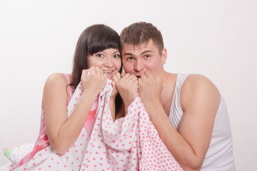 Young beautiful girl and the guy sitting in bed cuddling